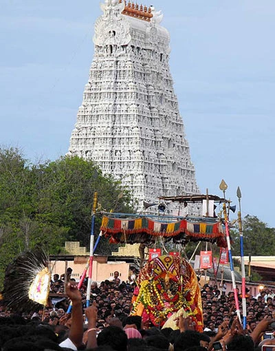 A decorated festival procession in front of Tiruchendur’s white temple tower